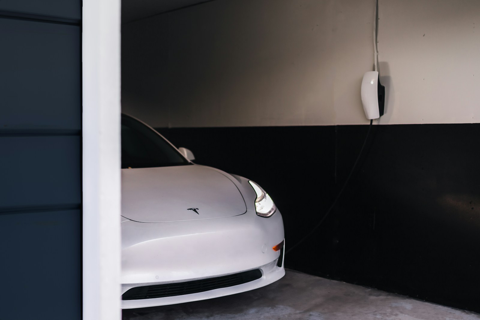 White electric vehicle charging inside a garage with no people present