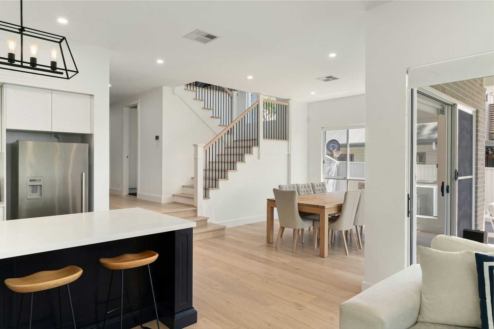 Open-plan home with a kitchen, staircase, dining area, and wall-mounted control